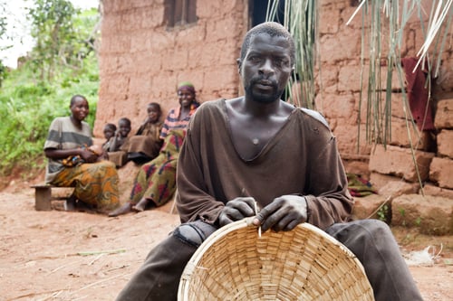 Preview: Man holding a basket with a group of people sitting in the background.