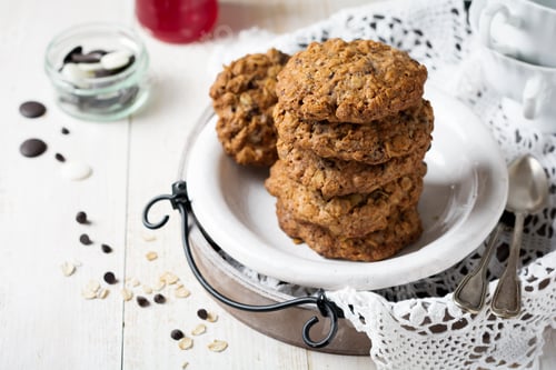 Preview: Stack of oatmeal cookies with chocolate on a light background with flakes and a bottle of milk. Sele