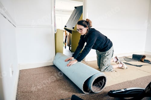 Preview: Woman rolling up old carpet in preparation to renew flooring