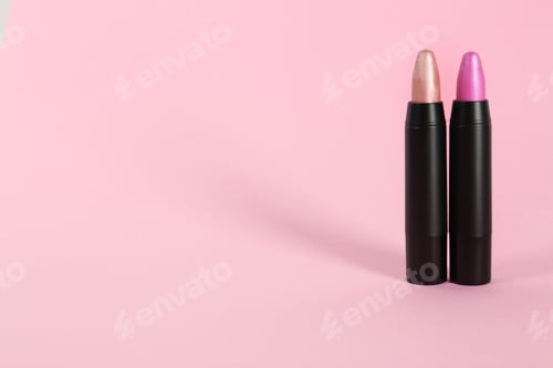 Preview: Bright lipsticks in black tubes on pink background, space for text