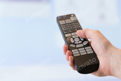Preview: Cropped male hand switches TV channels with a remote control close-up