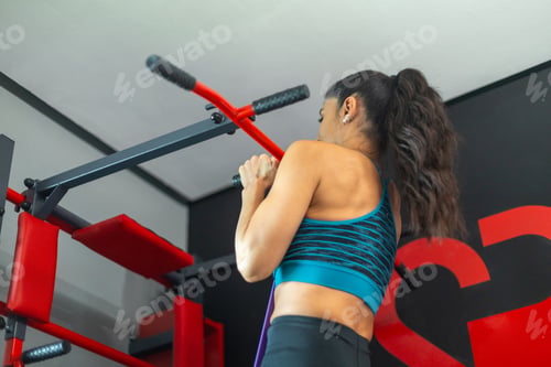 Preview: Determined sportswoman doing pull ups in modern fitness center, building strength and confidence