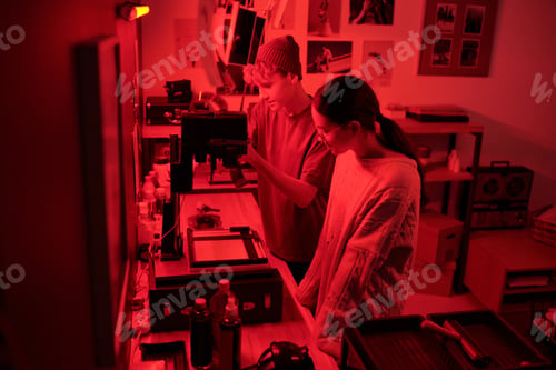 Preview: Two Photographers Working with Film Developing Photo Prints in Darkroom