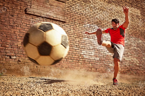 Preview: Young man kicking soccer ball on wasteland