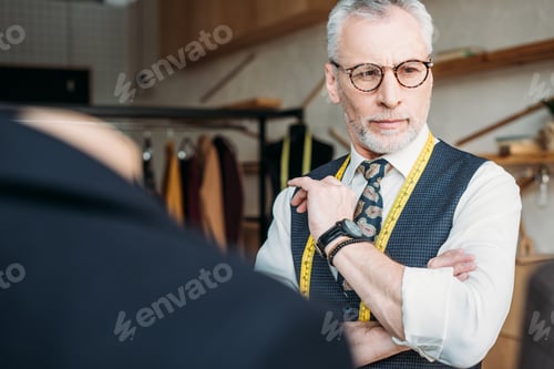 Preview: handsome grey hair tailor standing at sewing workshop