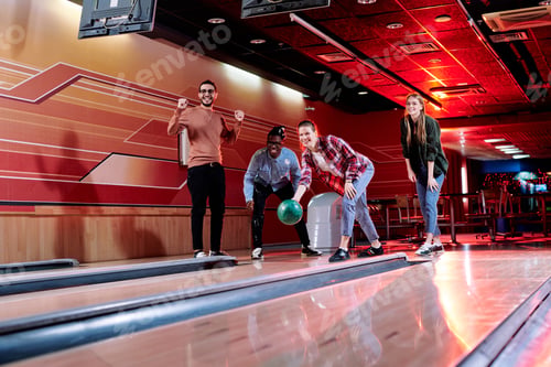 Preview: One of happy girls going to throw bowling ball on alley with friends near by