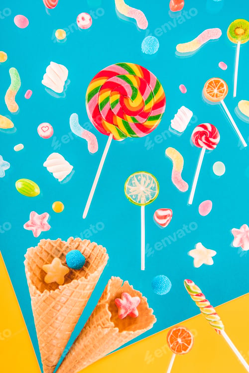 Preview: Close-up top view of tasty crispy waffle cones and different colorful candies isolated on blue and