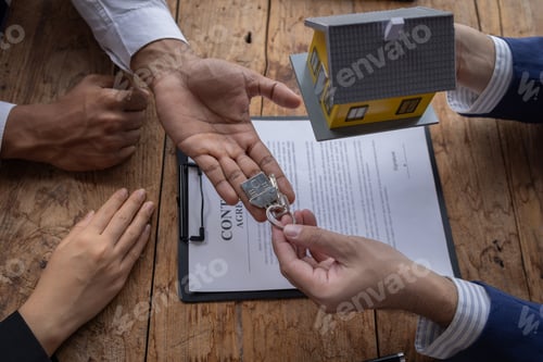 Preview: Sale agent giving house key to new client after signing agreement contract with approved property ap