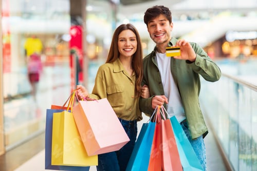 Preview: Couple Showing Credit Card Posing With Shopper Bags In Hypermarket