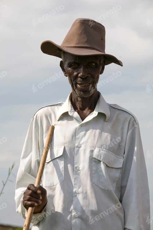 Preview: Friendly man in hat holding walking stick