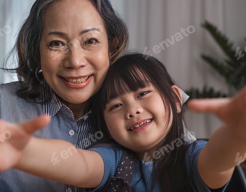 Preview: Grandma and granddaughter happily sit and play together in the living room.