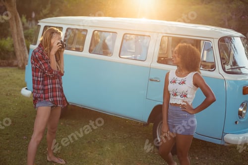 Preview: Woman taking a picture of her friend near campervan