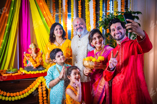 Preview: Indian Family Celebrating Ganesh Puja by Taking a Festive Selfie in Traditional Attire at Home
