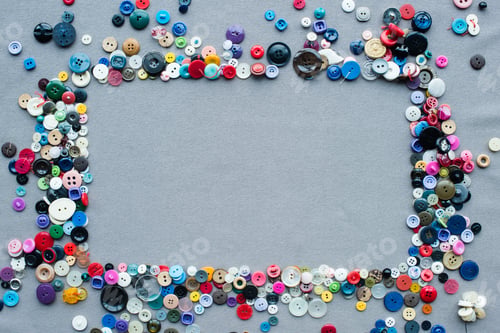 Preview: top view of colorful buttons frame on grey cloth background