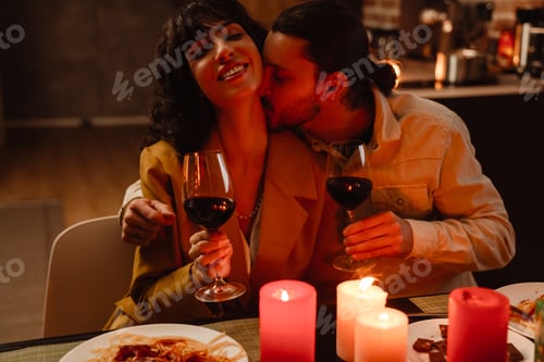 Preview: White couple kissing while having romantic dinner at home