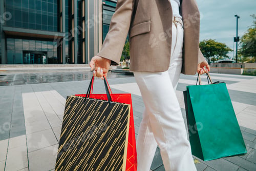 Preview: confident woman walking with shopping bags and neutral outfit