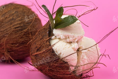 Preview: Vanilla ice cream balls in an empty coconut decorated with mint leaves on a pink background