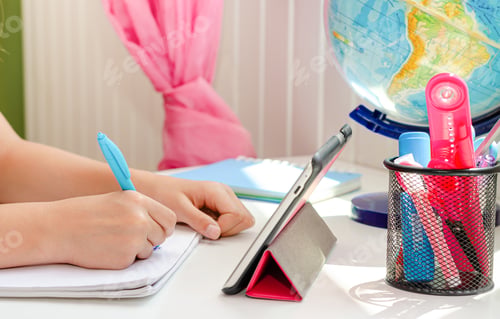 Preview: Hands of a child writing homework with tablet and stationery on white desk. Education concept