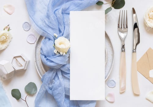 Preview: Card near blue tulle fabric knot and cream roses on plates top view copy space, wedding mockup