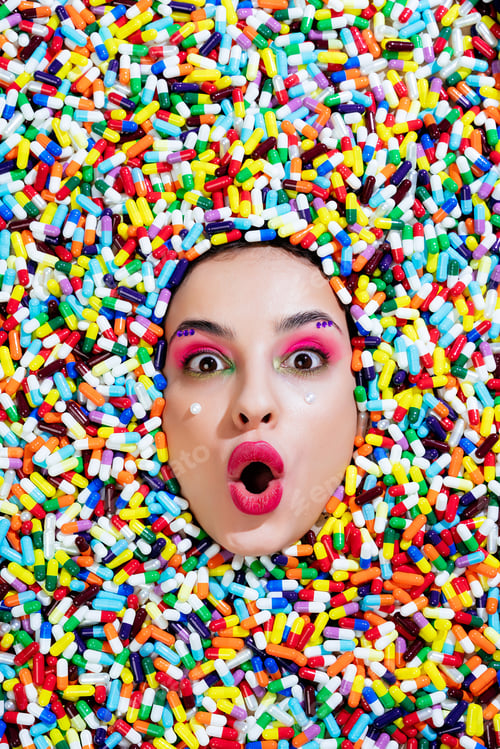 Preview: Artistic image of a beautiful woman sunk inside colored pills and capsules.