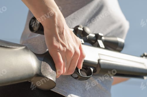 Preview: A woman is holding a large sniper rifle