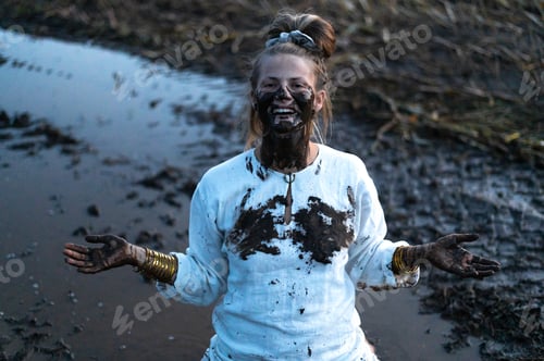 Preview: A happy authentic woman stuck in a mud puddle in a field