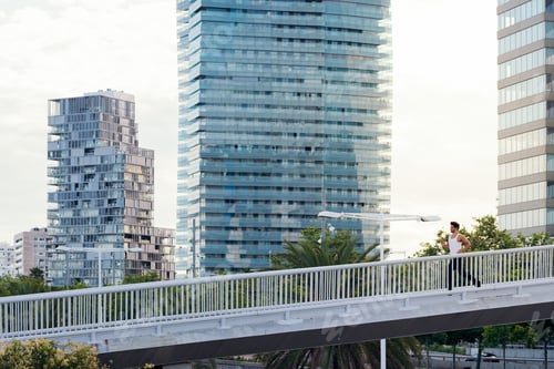 Preview: man running on a city bridge in front of buildings