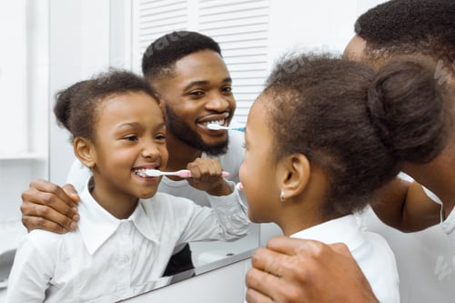 Preview: African-american girl brushing teeth together with dad