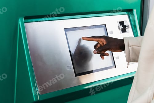 Preview: Anonymous black businessman touching screen of ATM in town