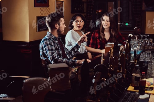 Preview: Group of happy multiracial friends resting and talking at bar or pub.