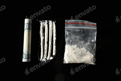 Preview: Drug addiction. Plastic bag with cocaine and rolled dollar banknote on black background, flat lay