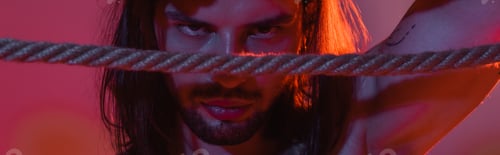 Preview: Long haired man looking at camera near rope on purple background with light, banner