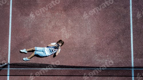 Preview: A kid photgrapher from a drone taking photos on a tennis court. Red colour and tone. White lines.