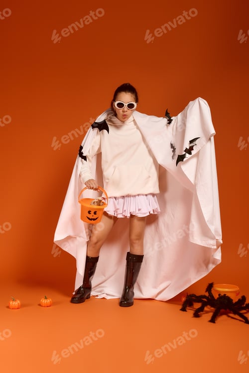 Preview: Cute girl in a spooky costume enjoys Halloween fun against an orange backdrop