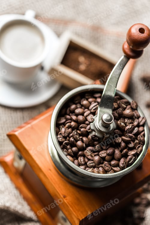 Preview: Grinding coffee beans in a traditional manual grinder with a cup in the background