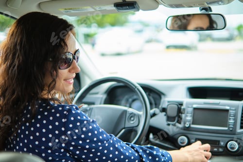 Preview: Young stylish woman driver sitting behind steering wheel of her car. Driving vehicle concept