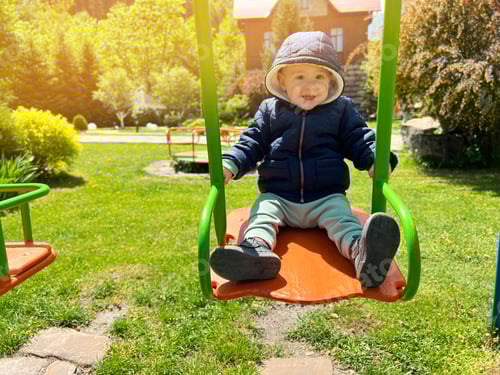 Preview: A cute boy of one and a half years rides on a swing. Backyard of the house. Indoor playground