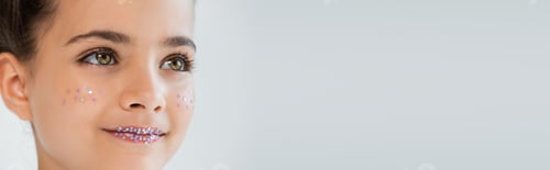 Preview: portrait of cheerful girl with sparkling glitter stars on lips and face looking away isolated on