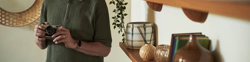 Preview: Man Holding Retro Camera While Standing by Wooden Shelf