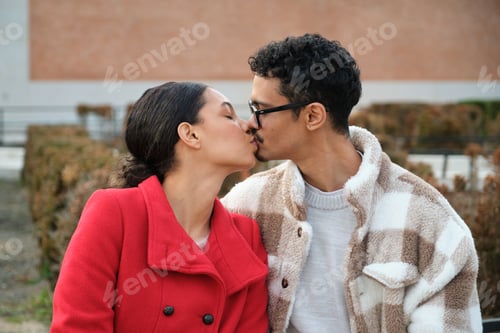 Preview: Young multiethnic couple kissing on a bench
