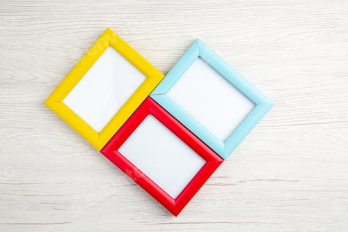 Preview: Above view of three empty picture frames in different colors on wooden stripped background