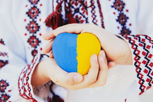 Preview: Girl in embroidery or embroidered shirt hold heart shape with Ukrane flag