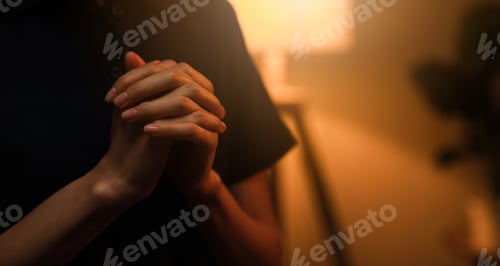 Preview: woman hand praying with magic light that flows through on orange bokeh background.