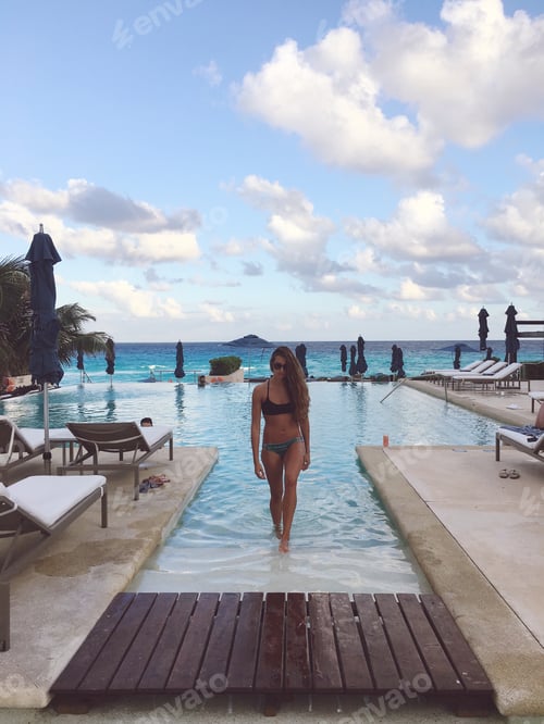 Preview: Woman walking out of the pool beach in background