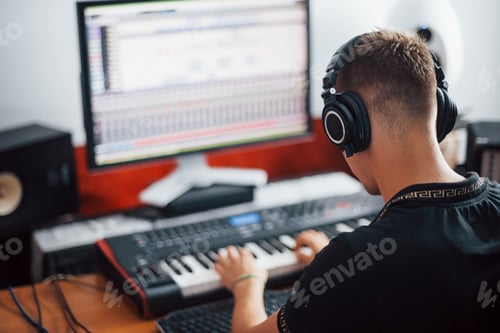 Preview: Sound engineer in headphones working and mixing music indoors in the studio