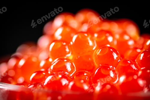 Preview: Grains of red caviar on a black background.