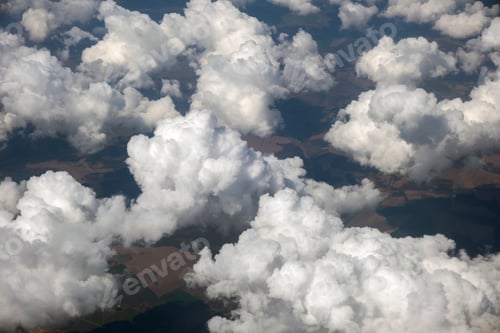 Preview: Aerial view from airplane window of white puffy clouds on bright sunny day