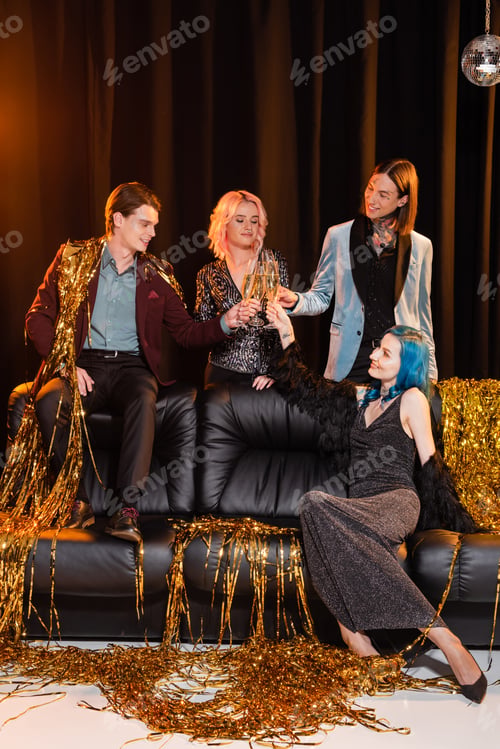 Preview: queer people in festive clothes clinking champagne glasses while celebrating christmas near golden