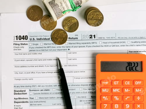 Preview: Close up of accountant filling individual income tax return form 1040 with coins, banknotes and calc