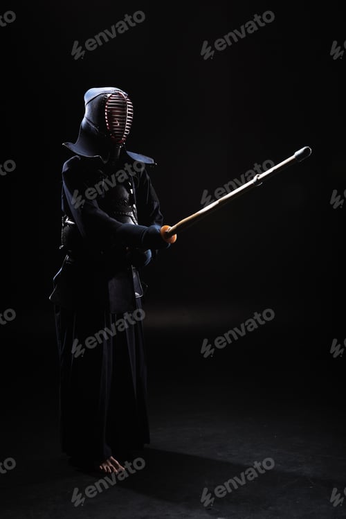 Preview: Full length view of kendo fighter in armor practicing with bamboo sword on black